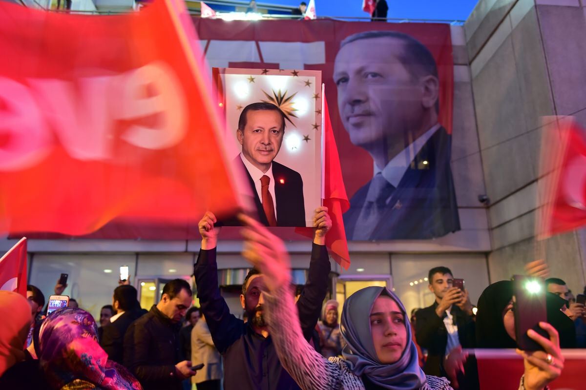 Crowd outside a building with a banner of Erdogan