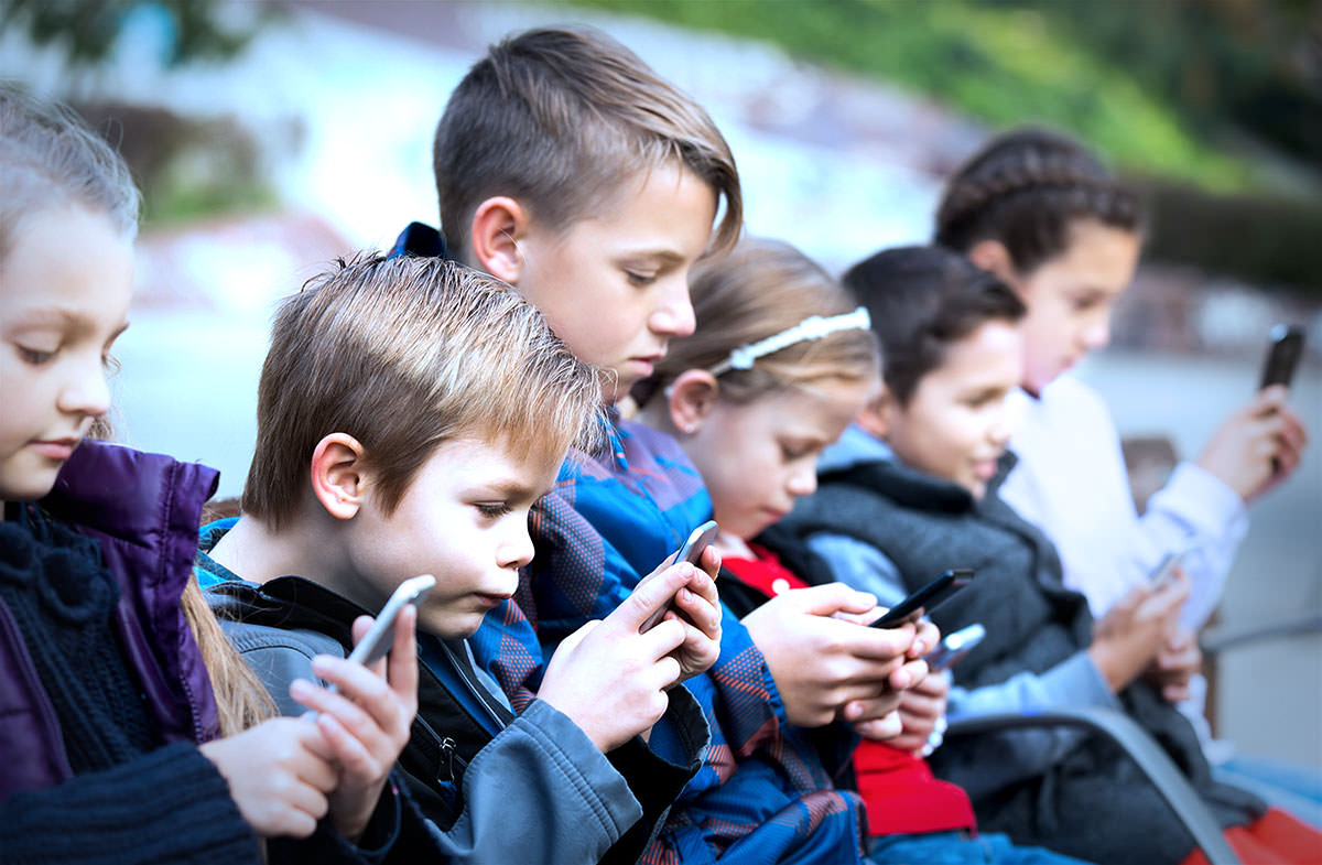 Kids looking at their phones. Photo by BearFotos.