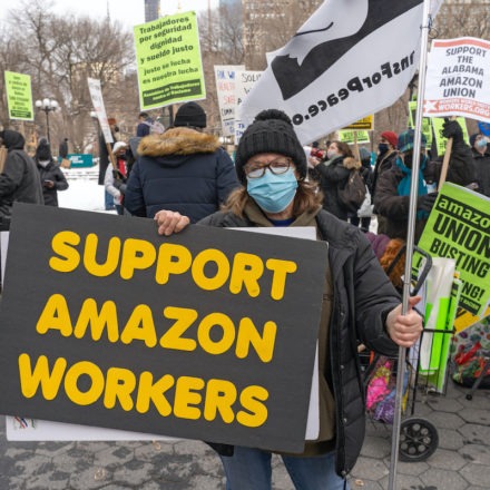Woman at a labor union protest holding a sign that says, "Support Amazon Workers"
