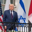 Donald Trump standing with the Israeli flag