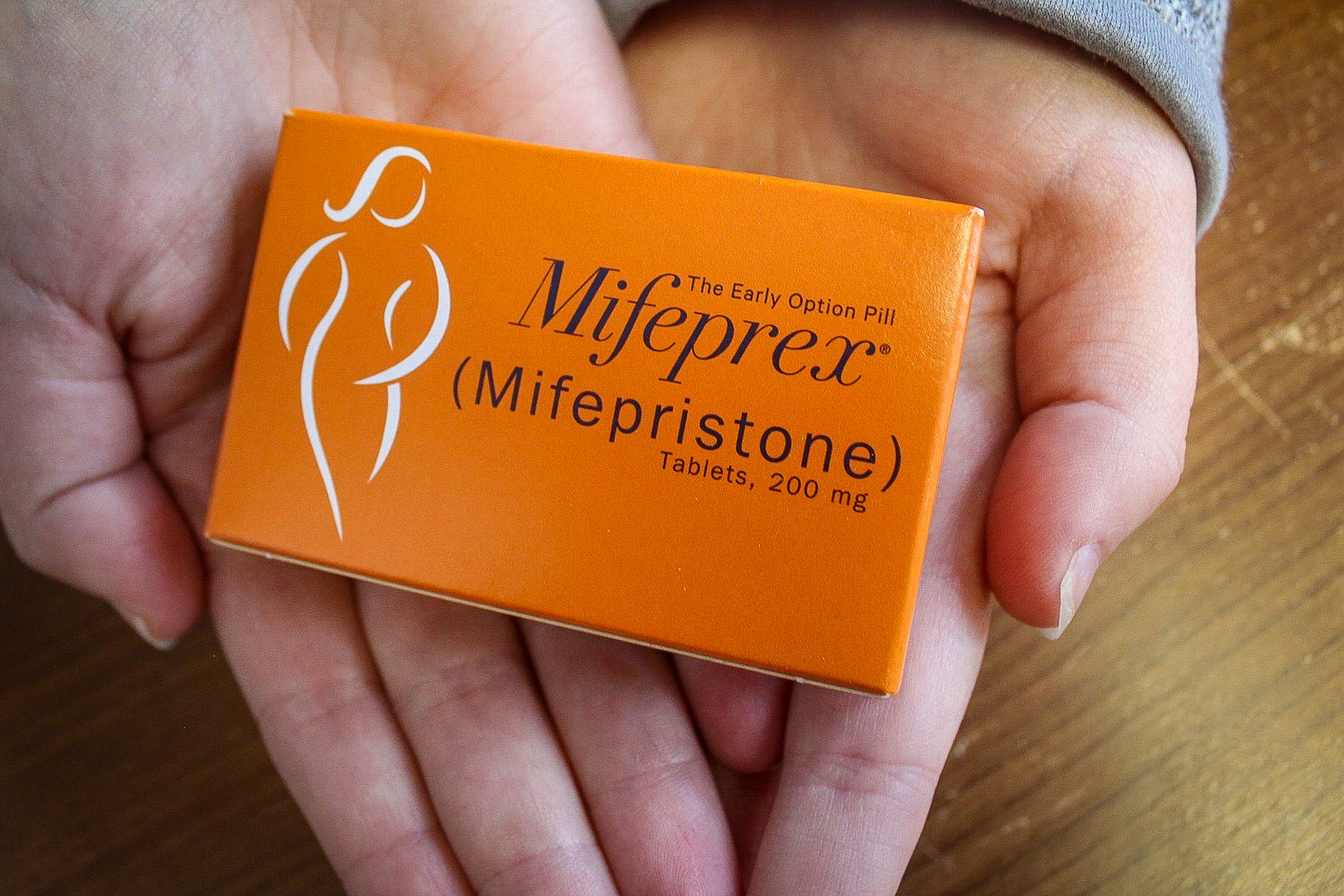 Two hands holding up a box of mifeprex, the abortion pill