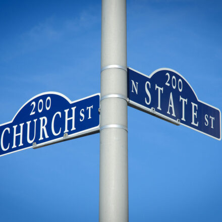 Street signs on a pole stating Church and State.