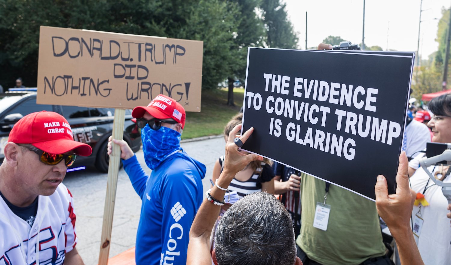 Atlanta, GA USA - August 24, 2023: A man holds sign that says "Donald J. Trump did nothing wrong" alongside woman holding anti-Trump sign on August 24, 2023 in Atlanta, GA.