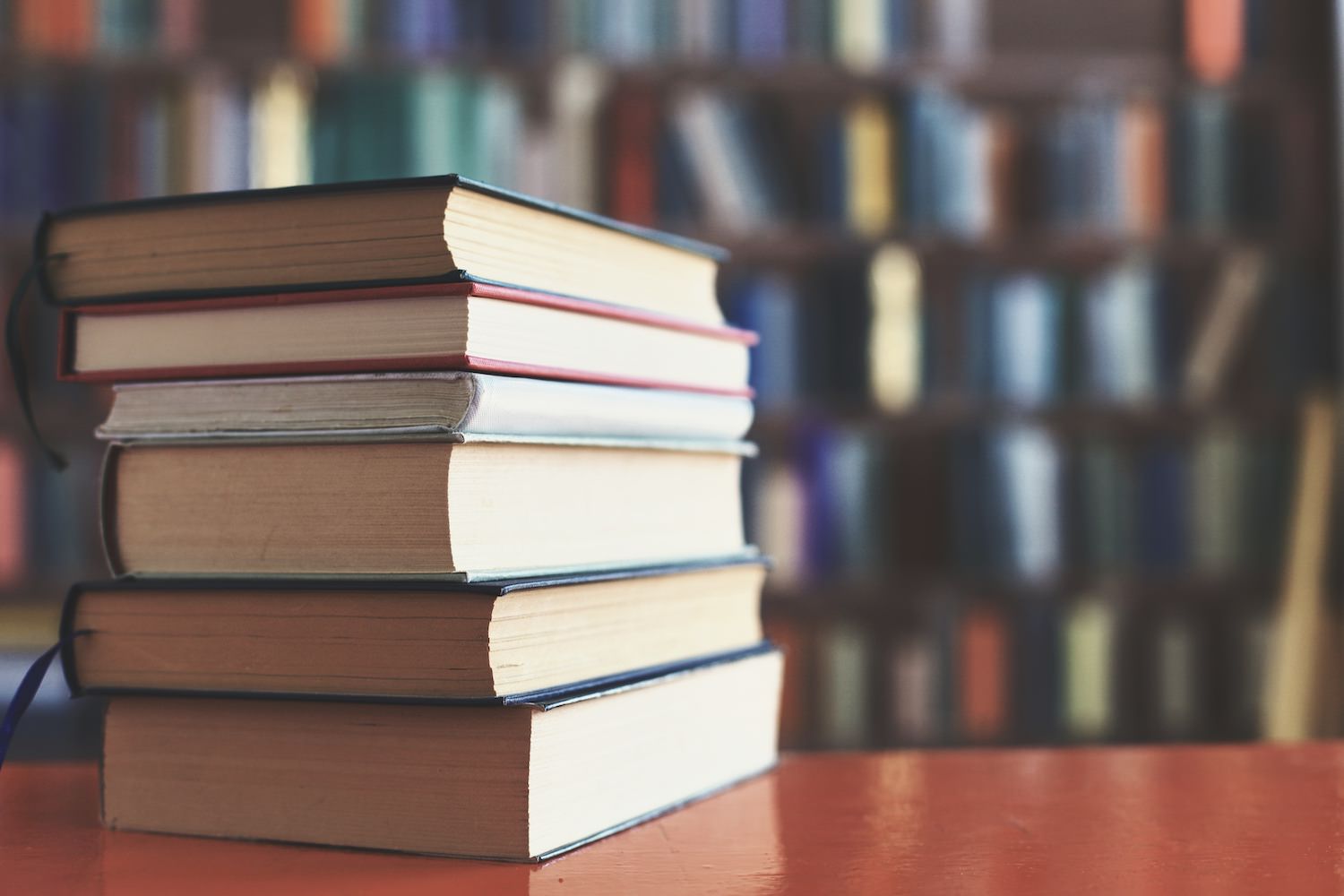 stack of books against the background of library, stack of books in front of library, books on wooden table