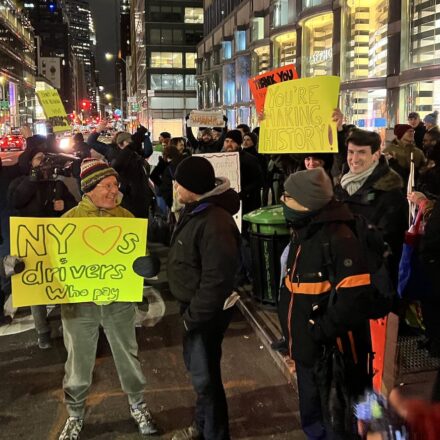 Congestion pricing supporters at Lexington Ave. and 60th Street, 12:03 a.m. Jan. 5, 2025. Author is at center, foreground, holding yellow sign. Photo: Sproule Love.