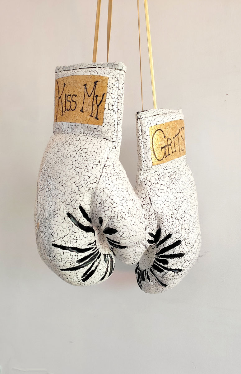 Borrowing from the traditional Vietnamese Sơn mài lacquer painting tradition, MyLoan Dinh delicately transformed a pair of boxing gloves with eggshell. The title, Kiss My Grits, is drawn from a deeply Southern expression of defiance made famous by the character Florence Jean "Flo" Castleberry on the 1970s sitcom Alice.
