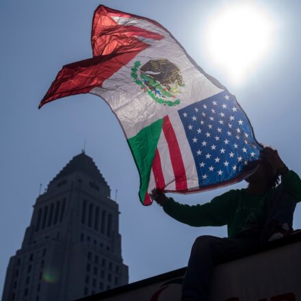 A man holds flag as community organizers protest outside the Federal Building following an immigration enforcement operation by federal authorities on Friday, June 6, 2025, in Los Angeles. Photo by Ringo Chiu.