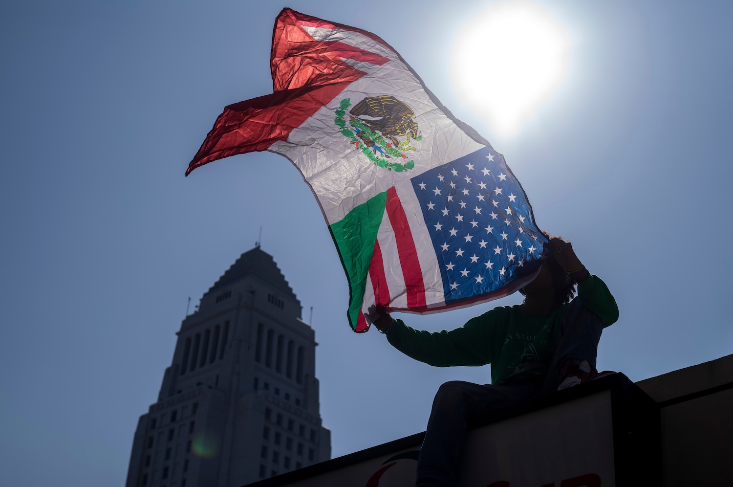 A man holds flag as community organizers protest outside the Federal Building following an immigration enforcement operation by federal authorities on Friday, June 6, 2025, in Los Angeles. Photo by Ringo Chiu.